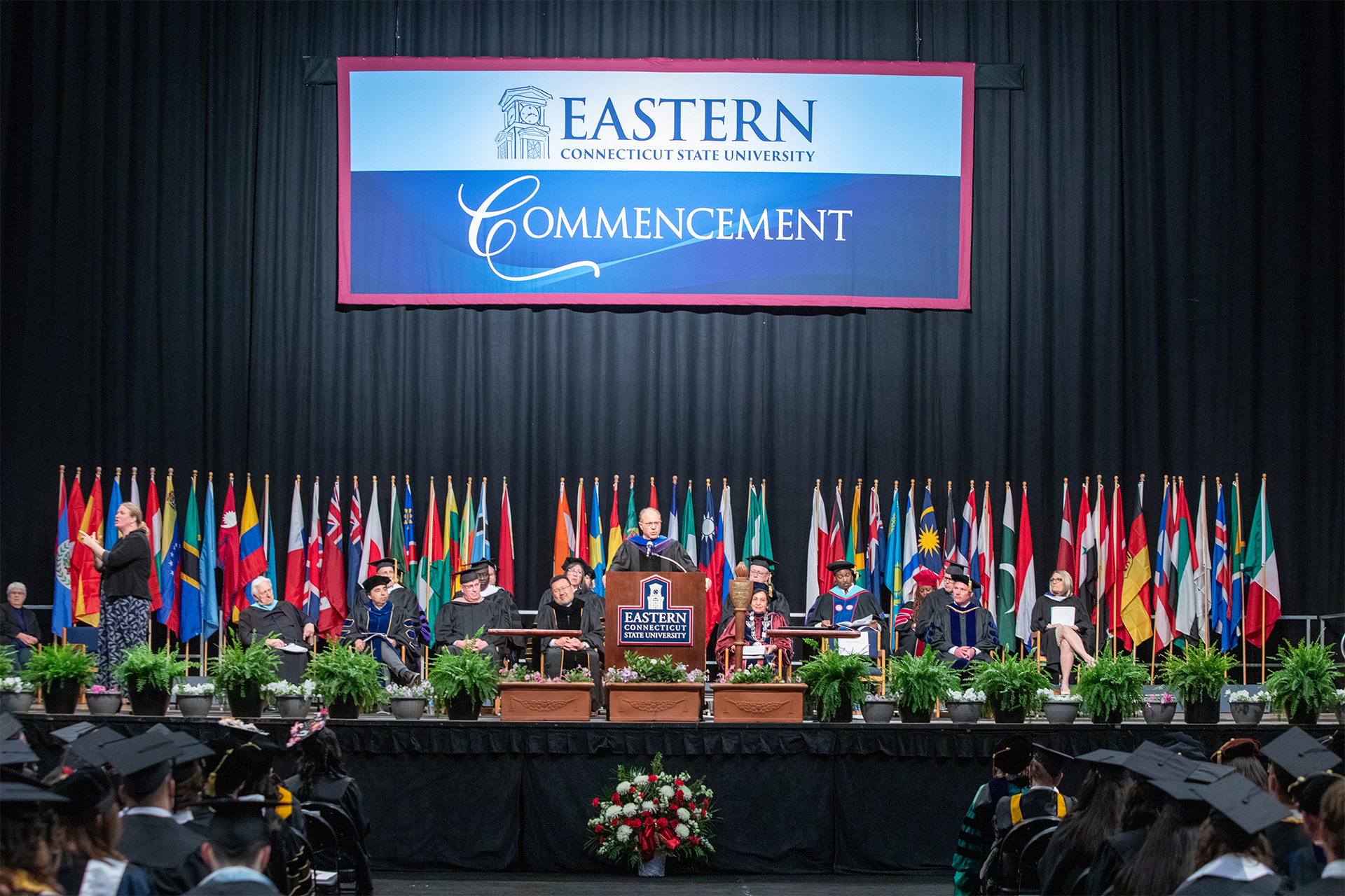 view of the Commencement stage, with flags behind the speaker