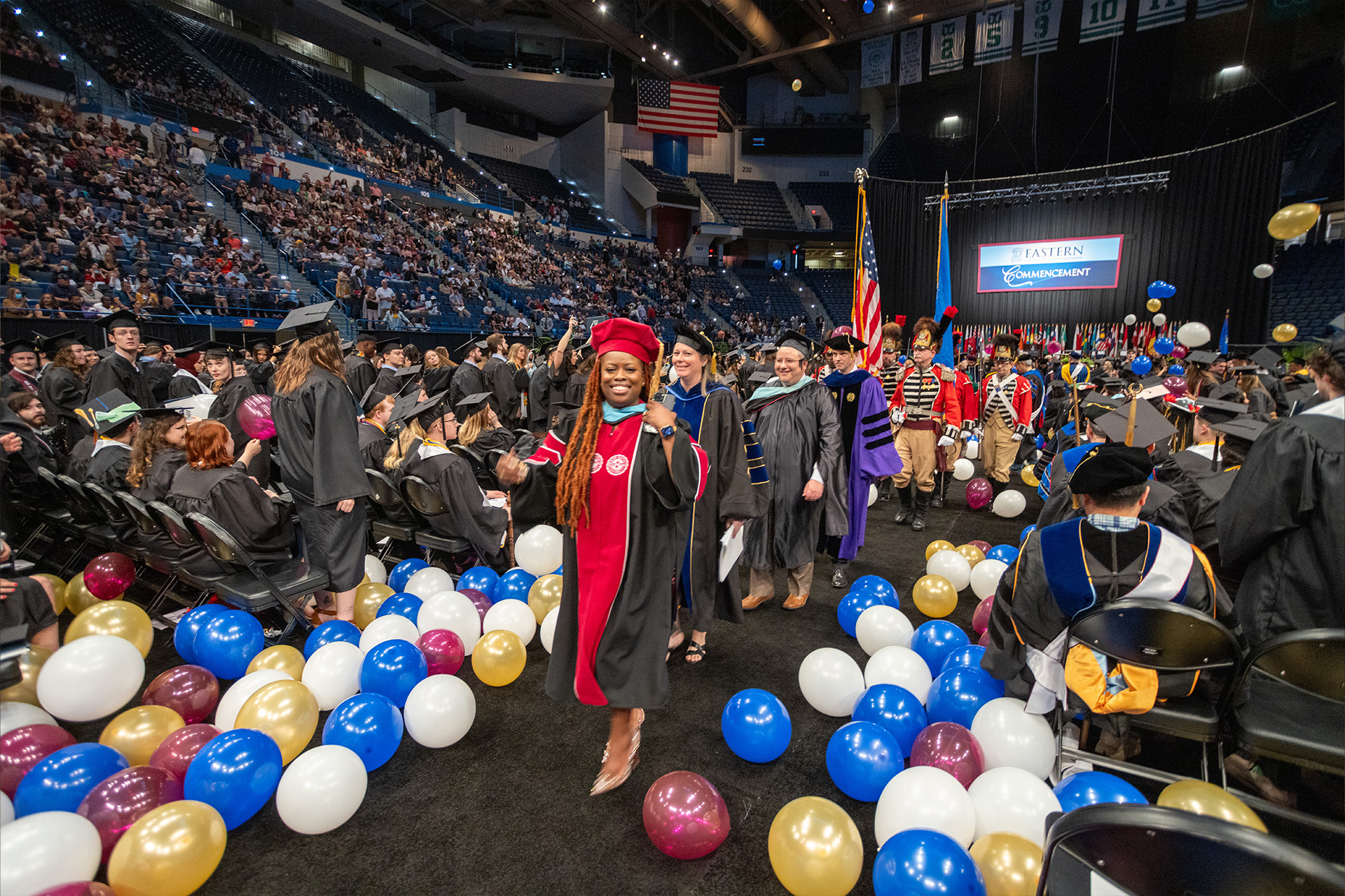 Professors walking down the aisle through colorful balloons as Commencement ends