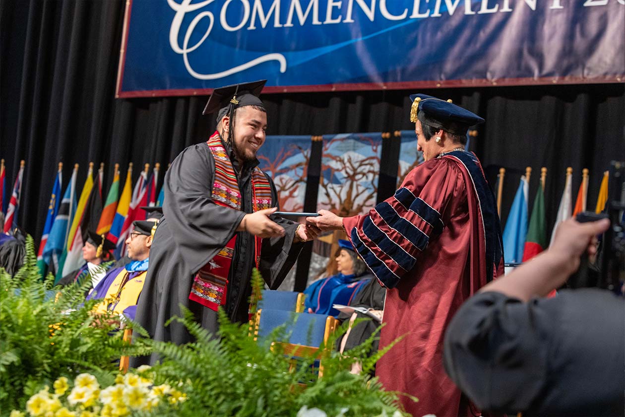 Dr. Núñez handing a diploma to a graduate