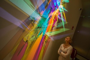 A gallery visitor gazes upward at another light painting