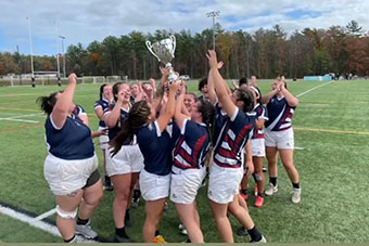 Women's rugby team holds up its trophy 