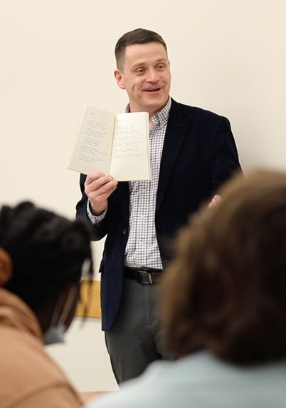 professor holding a book up to students