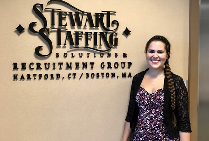 Student standing in front of business logo