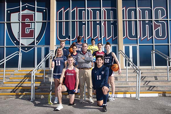 students and Bob Malta posing in front of the sports center