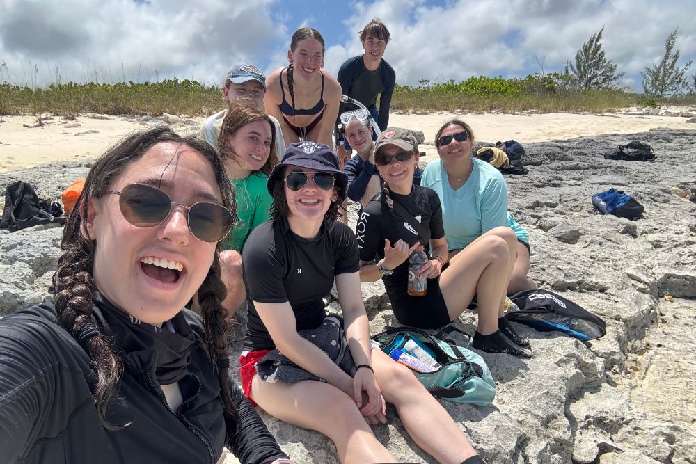 Isabella Symington-St. John (left) studies with peers on a beach in the Bahamas.