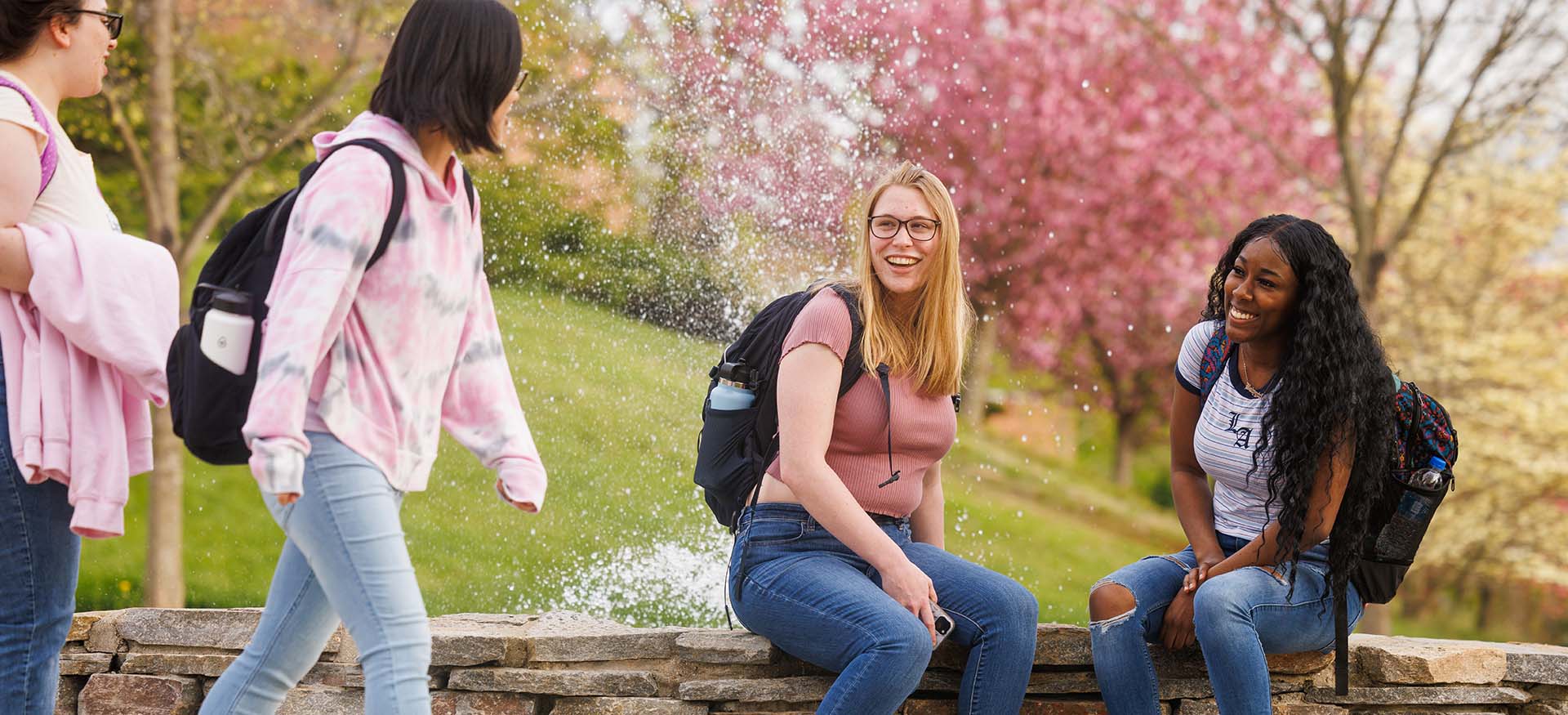 students hanging out by an outdoor fountain
