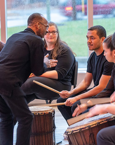 Teacher leading students in drum session