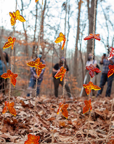 Orange plastic butterflies on string with students in the background