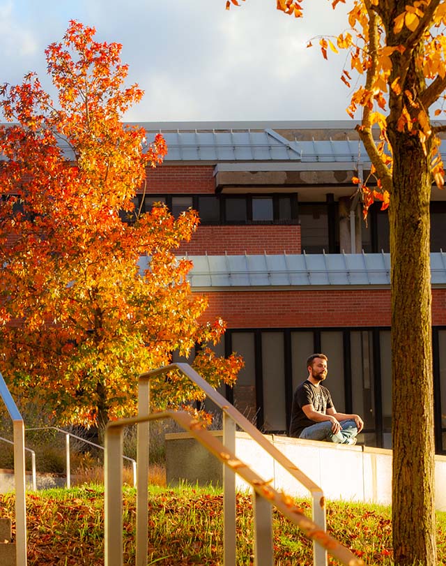 student enjoying the view surrounded by fall foliage