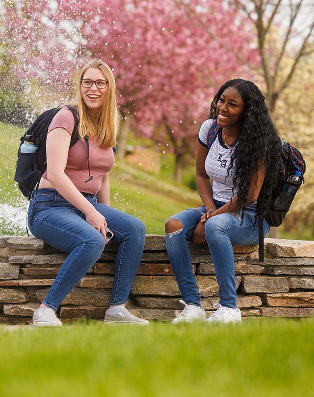 students hanging out by an outdoor fountain