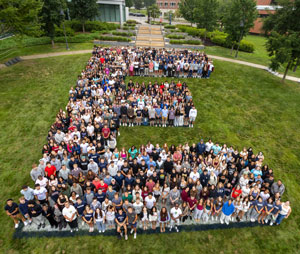 dozens of students gathered in the shape of a large E on the grass