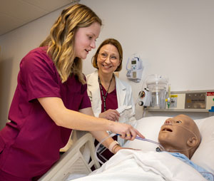 nursing student and professor working with training dummy