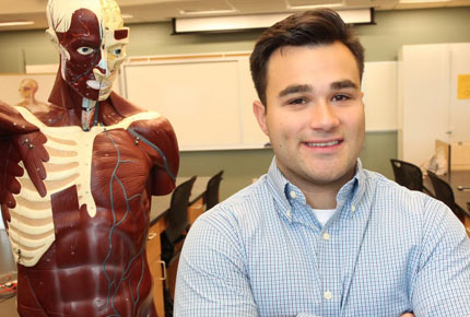 student standing in front of medical manakin