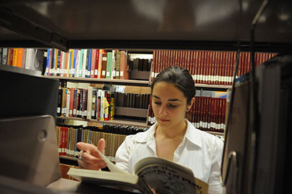 Decorative image of a student reading a book inside the library