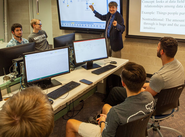 Professor teaching in front of screens