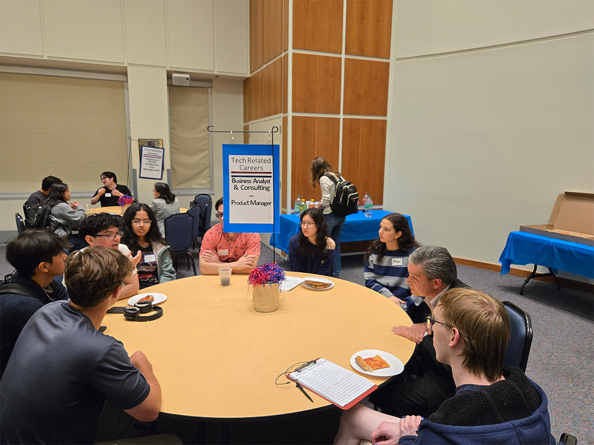 students sitting around a table with a sign that reads 'Tech Related Careers Business Analyst & Consulting - Product Manager'