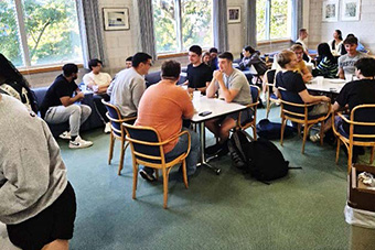  students sitting around a table talking 