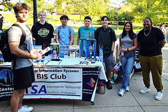  students standing around a BIS Club table at the student club fair 