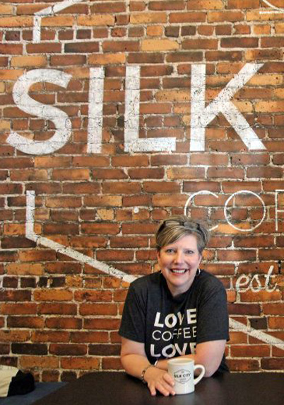 Tammy Gerhard in front of her coffee shop sign