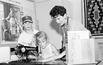 woman showing children how to use sewing machine