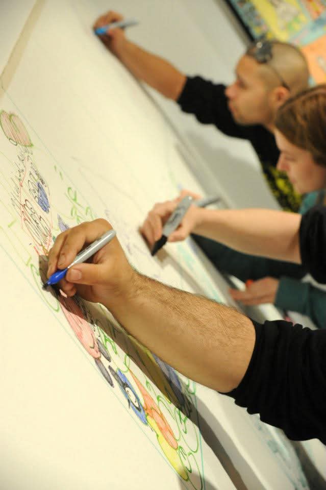 people drawing on the wall of the Akus Gallery