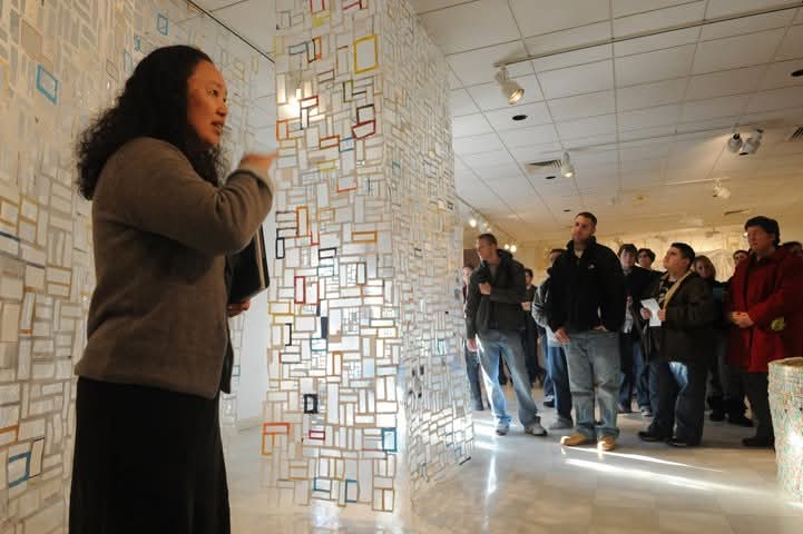 attendees listening to a guide during an Akus Gallery opening