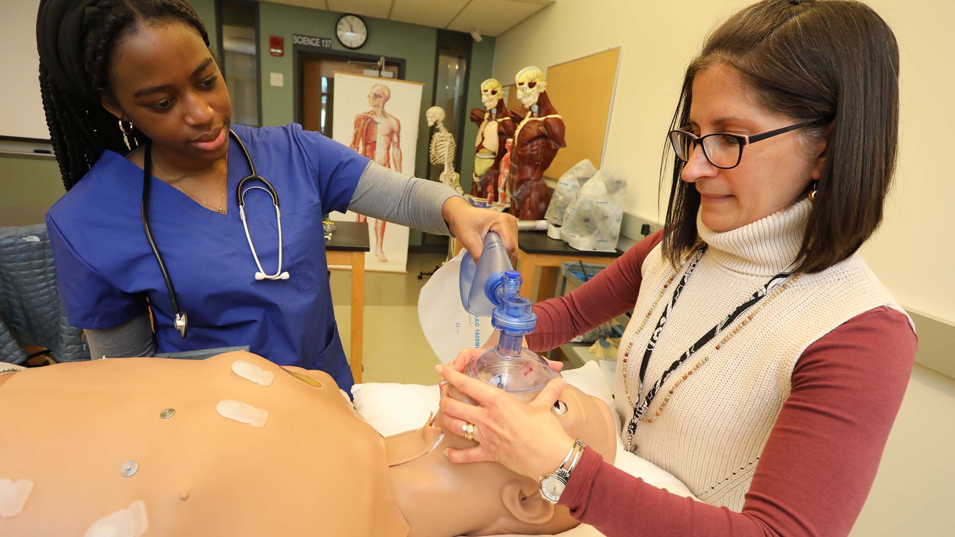 professor and nursing student using training dummy