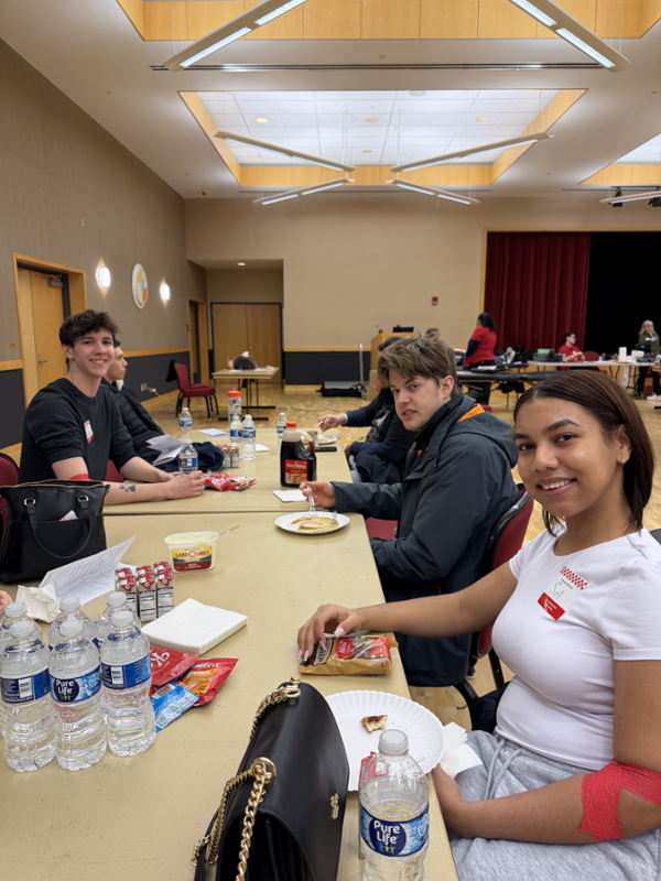 students sitting at a table with water, juice boxes and snacks on it