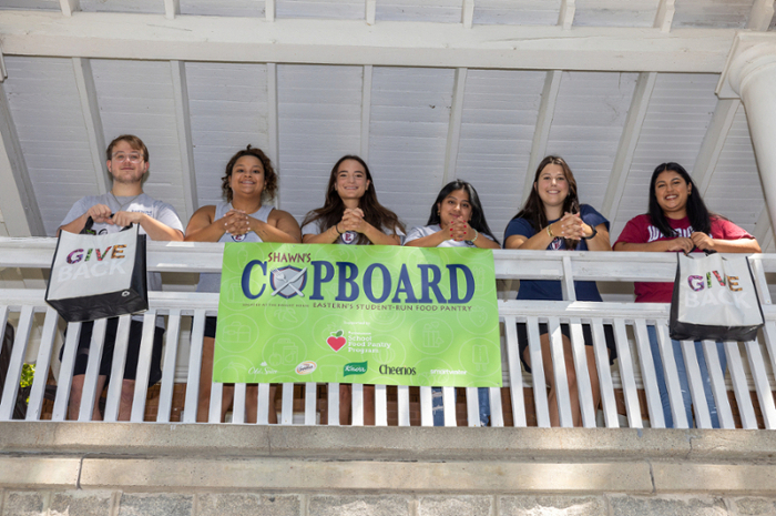Students looking over the Knight House balcony with a Shawn's Cupboard banner.