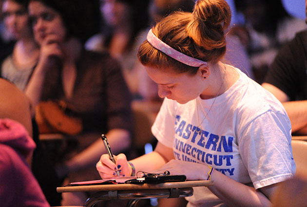 student writing on paper in a lecture hall