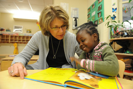 An adult reads a picture book to a preschooler