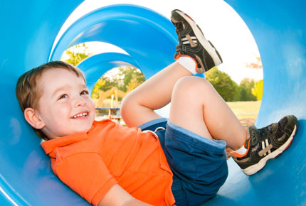 Preschooler plays inside a tunnel at a playscape