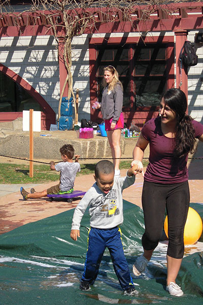 Children and teachers play in various obstacle course challenges. 