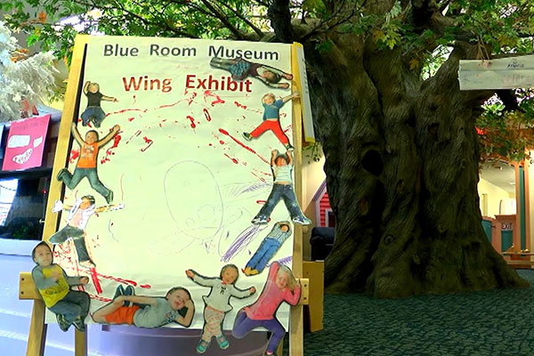 A sign with the text "Blue Room Museum Wings Exhibit"