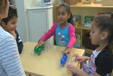 Children playing a sorting game with colored eggs.