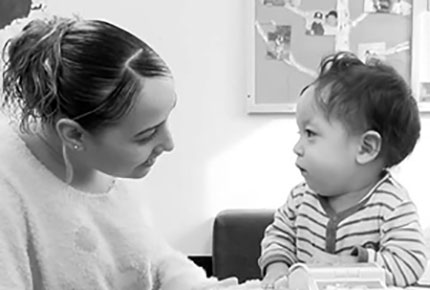 A teacher plays with a toddler. 