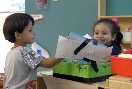 Two preschoolers pretend to be cashier and customer in a grocery store dramatic play center