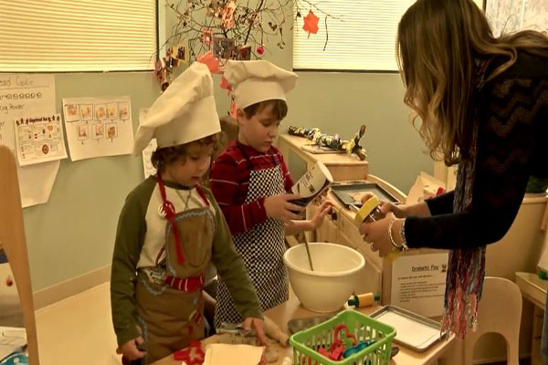 Children pretend to be working in a bakery as their teacher orders food. 