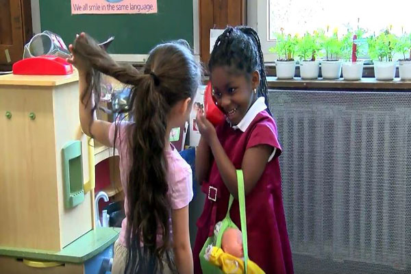 Two girls play dress-up. One pretends to be on the phone.