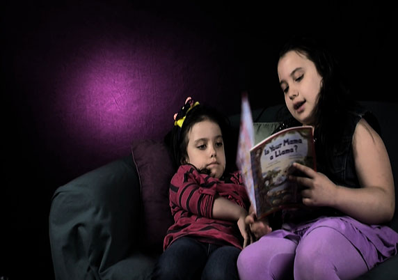 Sisters read together on the couch.