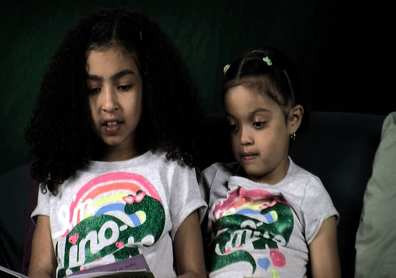 Sisters read together on the couch.