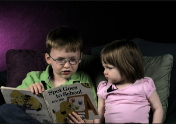An older brother reads to his little sister.