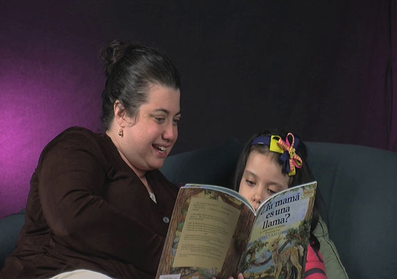 Two sisters read together on a couch.