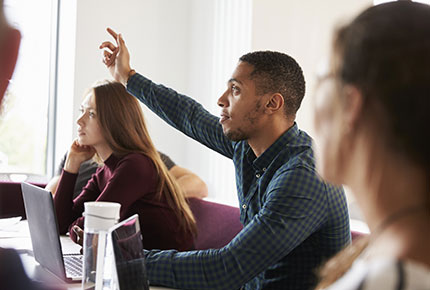 image of a college student raising his hand to respond to a question