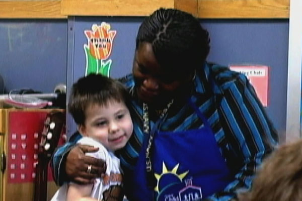 A teacher hugs a child.