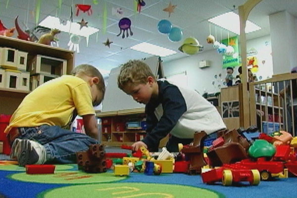 Two children play with Lego vehicles in the block area.