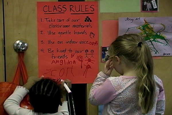 Two children read a poster with Class Rules written on it.