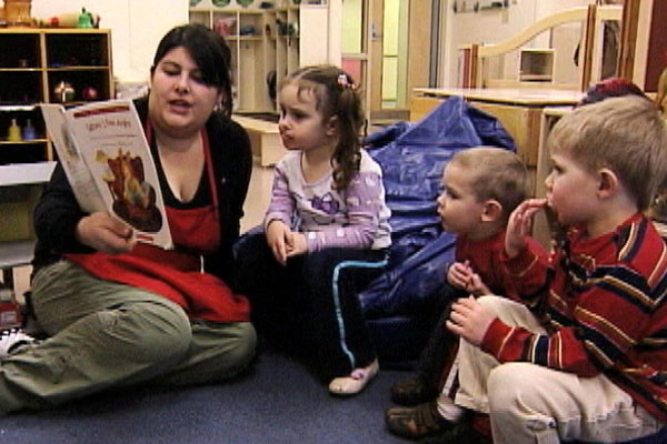 A preschool teacher reads to three children