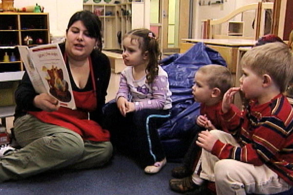 A teacher reads a book to a group of children.