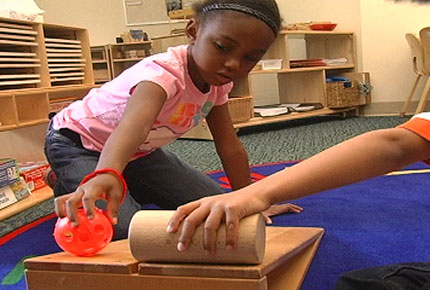 Children rolling a ball down a ramp